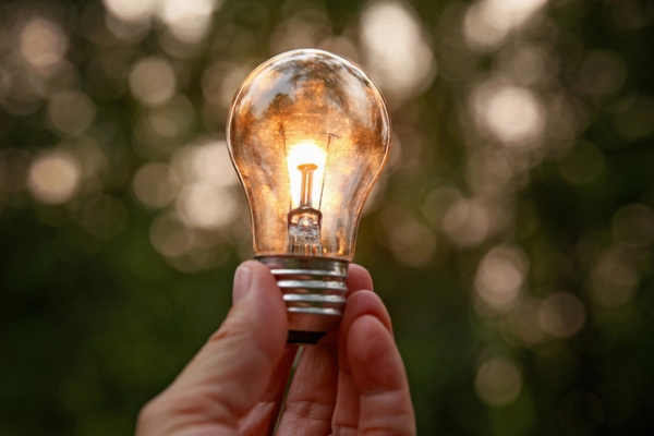 hand holding incandescent light depicting less energy efficiency