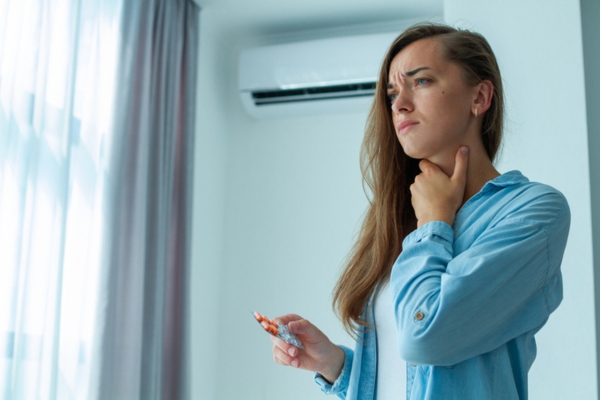 homeowner in front of ductless air conditioner depicting poor indoor air quality