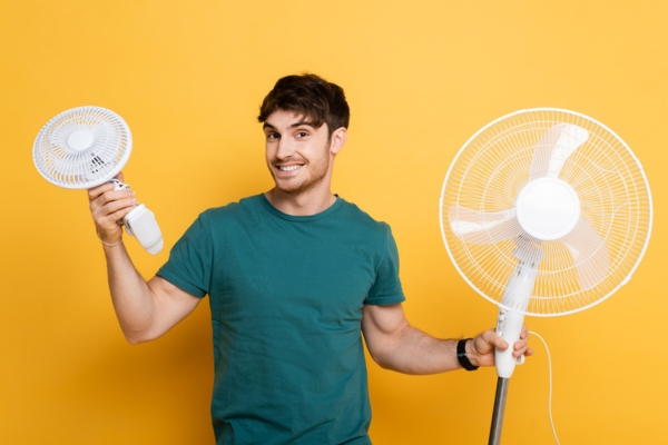 man holding two fans on each hand depicting temporary cooling solution