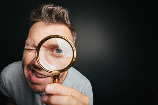 man looking through magnifying glass depicting signs of an aging furnace