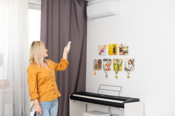 woman adjusting air conditioner temperature depicting HVAC best practices