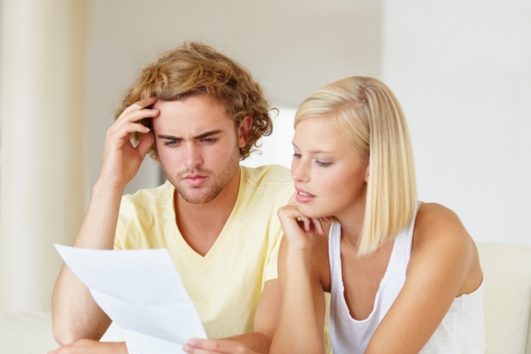 young couple looking at high energy bill caused by air leaks at home